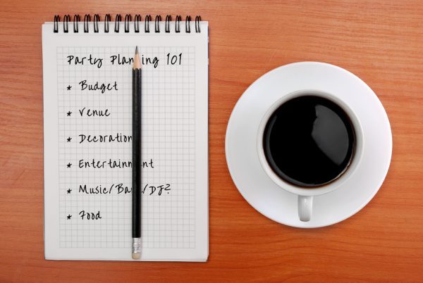 notes on how to plan a party, notepad on a wooden desk with a cup of coffee